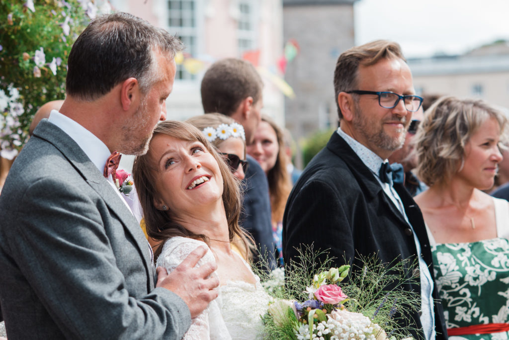 Bride and groom look lovingly into each others eyes surrounded by family and friends