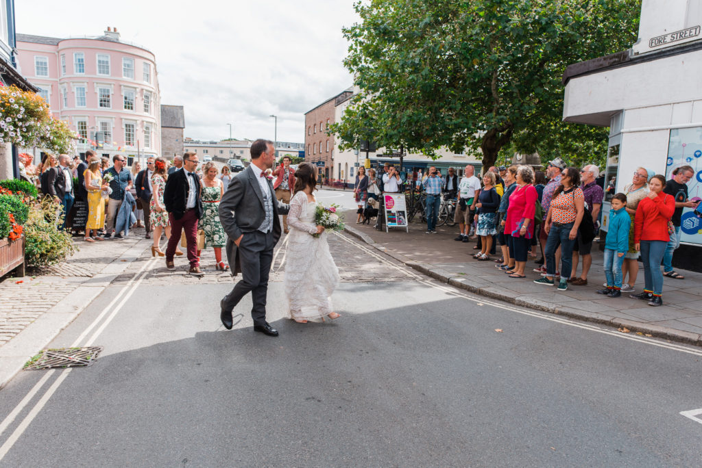 Bride and groom begin to lead procession of wedding party up Totnes high street