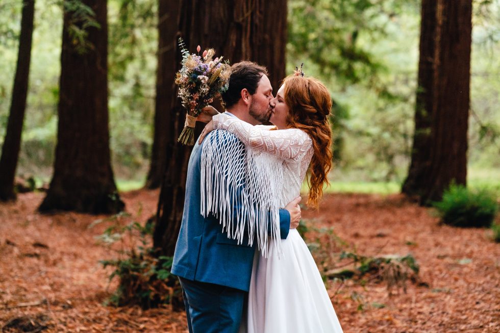Couple kissing in the woods during their colourful wedding in devon